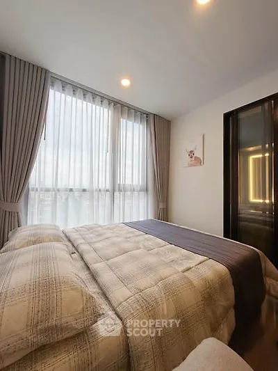 Cozy bedroom with large window and elegant curtains, perfect for relaxation and comfort.