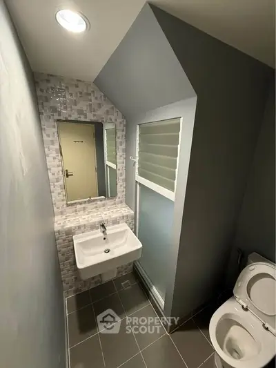 Modern bathroom with sleek design, featuring a wall-mounted sink and contemporary fixtures.