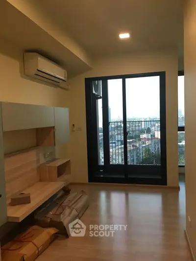 Modern apartment interior with large window and city view, featuring sleek built-in furniture and air conditioning.