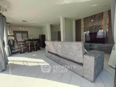 Spacious modern living room with open layout and stylish decor, featuring a large TV and elegant furnishings.