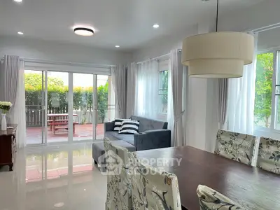 Spacious living room with elegant dining area and large windows opening to a garden view.
