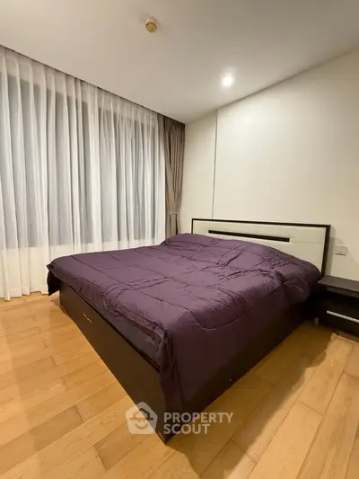 Spacious bedroom with elegant wooden flooring and modern bed design