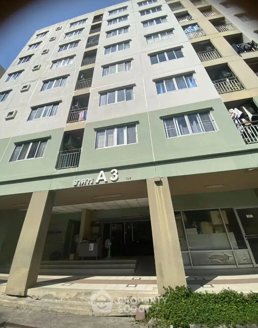 Modern apartment building exterior with multiple balconies and green facade.