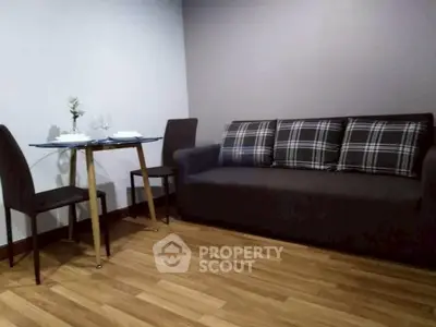 Cozy living room with stylish sofa and dining table on wooden flooring.