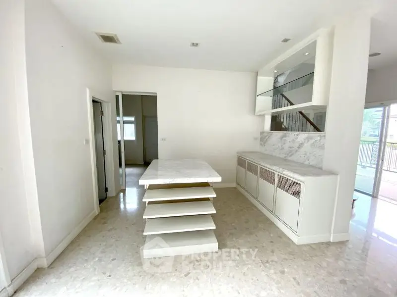 Spacious interior with marble island and built-in shelving, perfect for modern living.