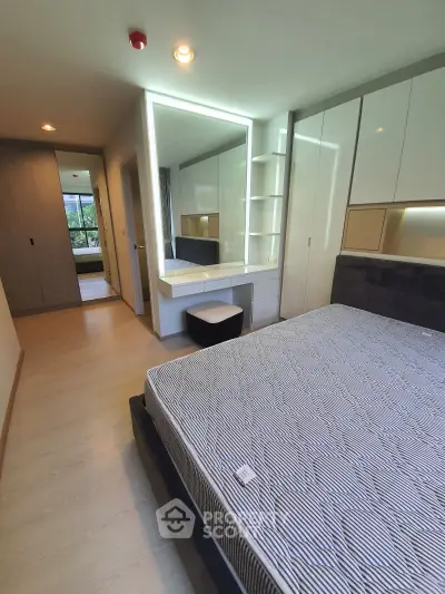 Modern bedroom with built-in wardrobe and large mirror, featuring sleek design and ample natural light.