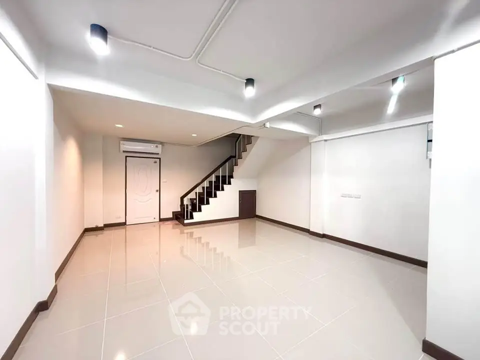 Spacious modern living room with sleek staircase and bright lighting