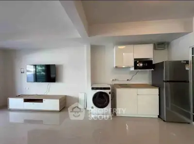 Modern open-plan living room with sleek kitchen appliances and wall-mounted TV.