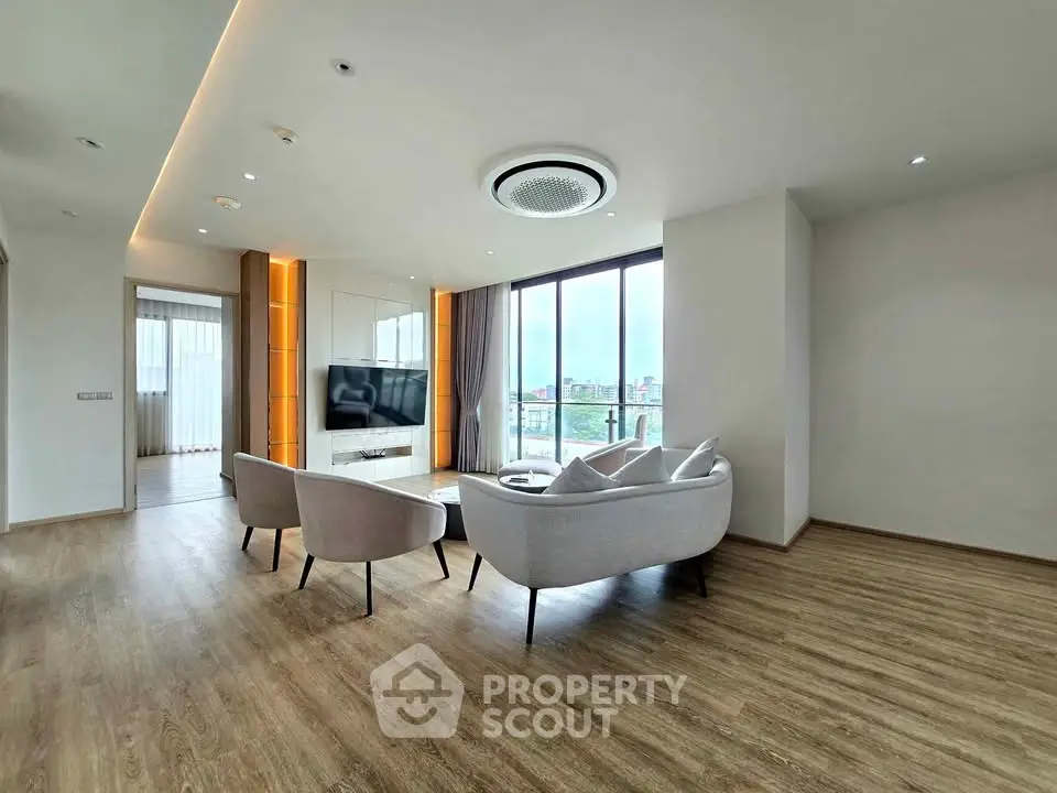 Spacious modern living room with elegant furniture and large windows offering a stunning city view.