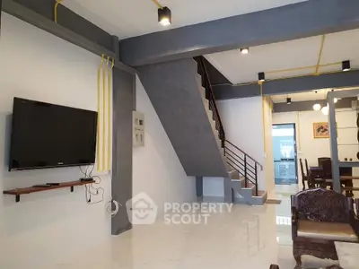Modern living room with sleek staircase and wall-mounted TV in open layout.