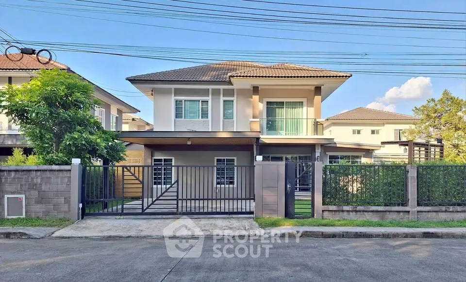 Modern two-story house with gated entrance and lush greenery
