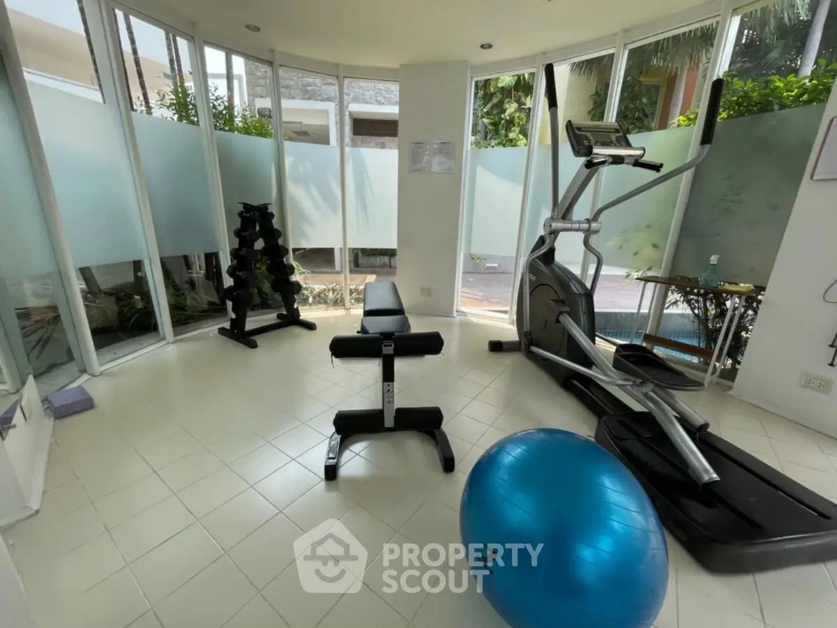 Modern home gym with treadmill, weights, and exercise ball in bright room