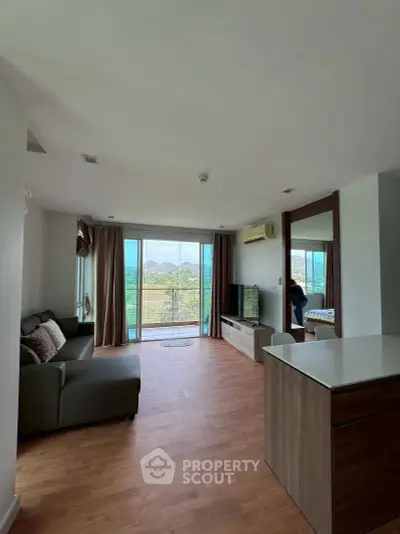 Spacious living room with large windows and scenic view, modern furnishings, and wooden flooring.