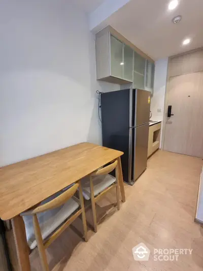 Modern kitchen with wooden dining table and sleek refrigerator in cozy apartment.