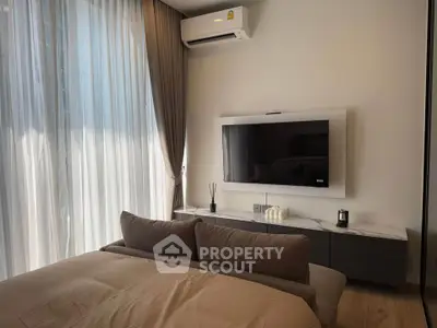 Modern bedroom with sleek TV setup and elegant curtains