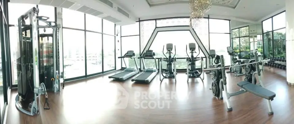 Luxurious gym with panoramic windows and modern fitness equipment in upscale residential building.