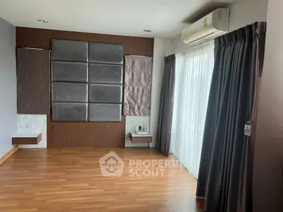 Spacious modern living room with wooden flooring and large windows for natural light.