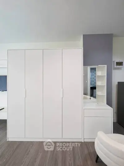 Modern white wardrobe and vanity set in a stylish bedroom with sleek design and ample storage space.