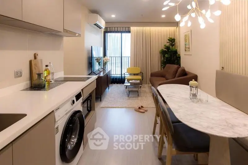 Modern living room with open kitchen, stylish decor, and natural light