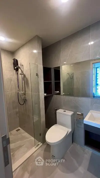 Modern bathroom with sleek design, featuring a glass shower enclosure and contemporary fixtures.