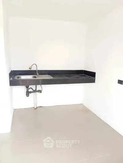 Minimalist kitchen with sleek black countertop and stainless steel sink