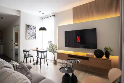 Modern living room with stylish decor and large TV, perfect for entertainment.