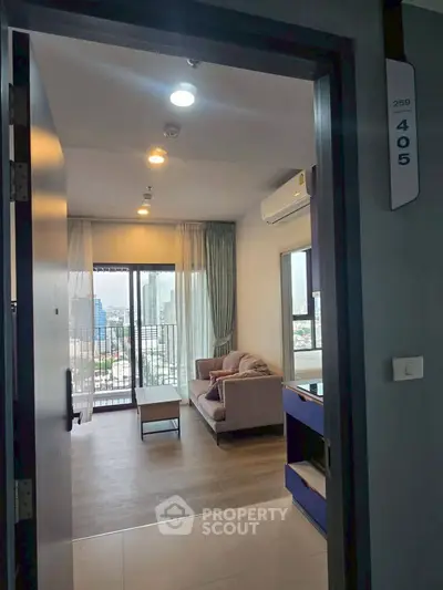 Modern living room with city view and balcony access in high-rise apartment.