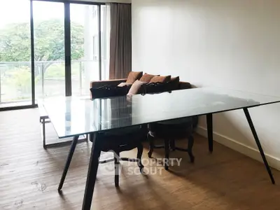 Spacious living room with glass table and balcony view, perfect for modern living.