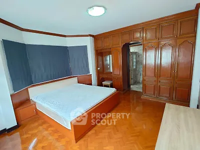 Spacious bedroom with wooden furniture and large windows in a modern home.