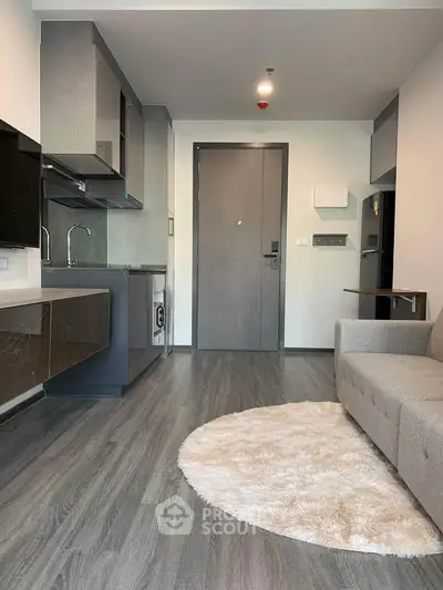 Modern living room with sleek kitchen, cozy sofa, and stylish flooring in a contemporary apartment.