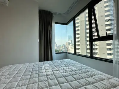 Modern bedroom with large windows offering stunning city views in a high-rise building.