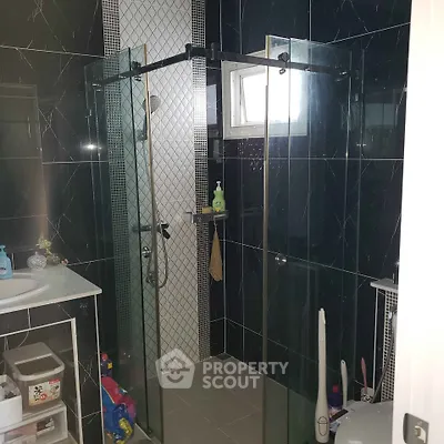 Modern bathroom with sleek black tiles and glass shower enclosure