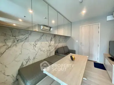 Modern living room with marble accent wall and sleek furniture in a stylish apartment.