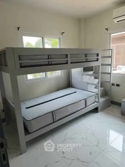 Modern bedroom with stylish bunk bed and large windows for natural light.