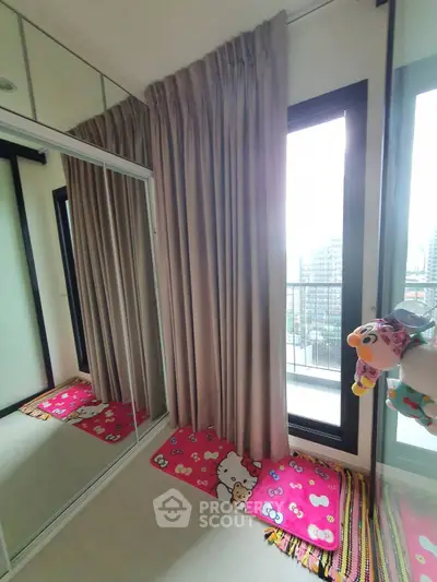Cozy bedroom with mirrored closet and balcony view, featuring playful decor and ample natural light.