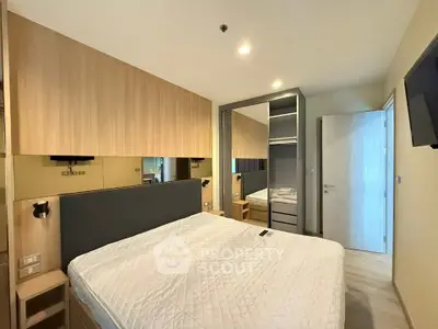 Modern bedroom with stylish wooden accents and mirrored wardrobe in a cozy apartment.