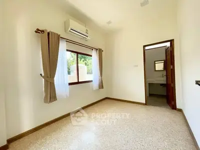 Bright bedroom with air conditioning and window view, featuring neutral decor and polished flooring.