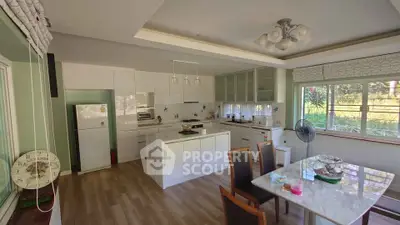 Spacious kitchen with modern appliances and dining area, featuring large windows and elegant decor.