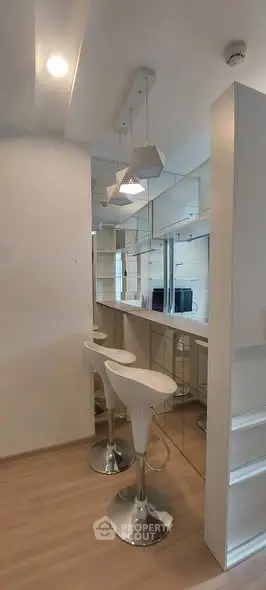 Modern kitchen with sleek bar stools and mirrored backsplash
