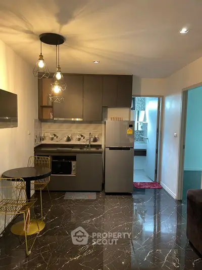 Modern kitchen with sleek design, marble flooring, and stylish lighting in a cozy apartment.