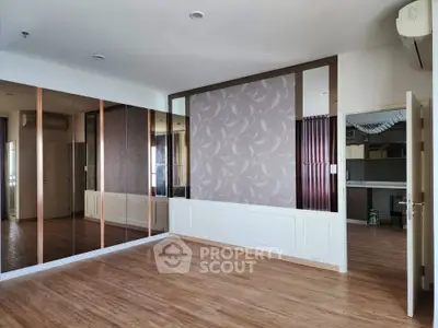Spacious empty living room with wooden flooring and mirrored wall, perfect for customization.