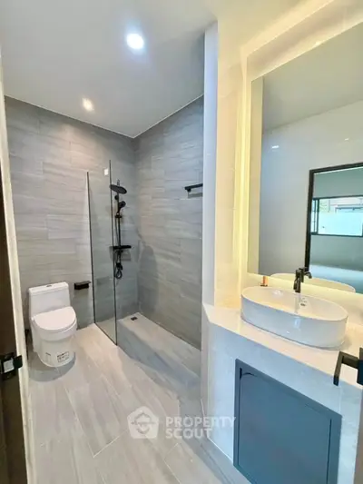 Modern bathroom with sleek design, featuring a spacious shower and elegant vanity.