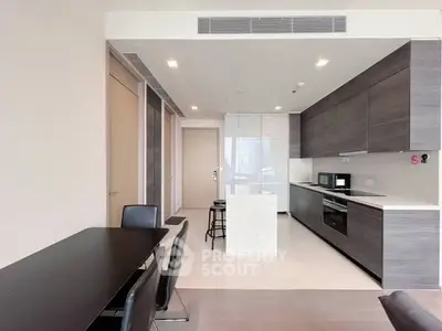 Modern kitchen with sleek cabinetry and dining area in open layout apartment.