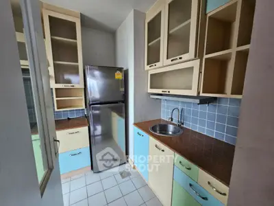 Charming compact kitchen with colorful cabinets and stainless steel fridge