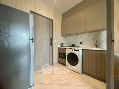 Modern kitchen with sleek appliances and marble backsplash in contemporary apartment.