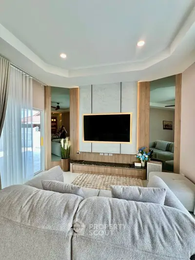 Spacious modern living room with stylish decor and large TV, perfect for relaxation.