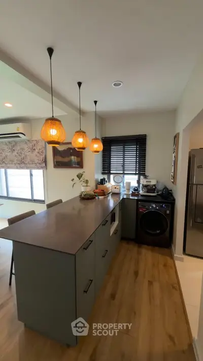 Modern kitchen with island, pendant lights, and integrated appliances in stylish home.