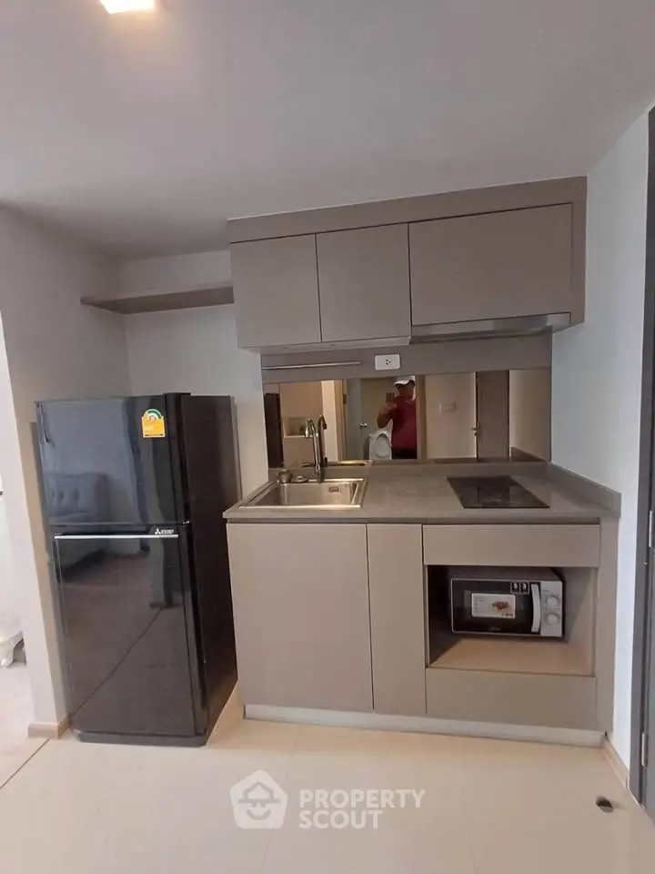 Modern compact kitchen with sleek cabinetry and built-in appliances in a stylish apartment.