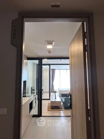 Modern apartment entrance with open view to living room and bedroom, featuring sleek design and natural light.
