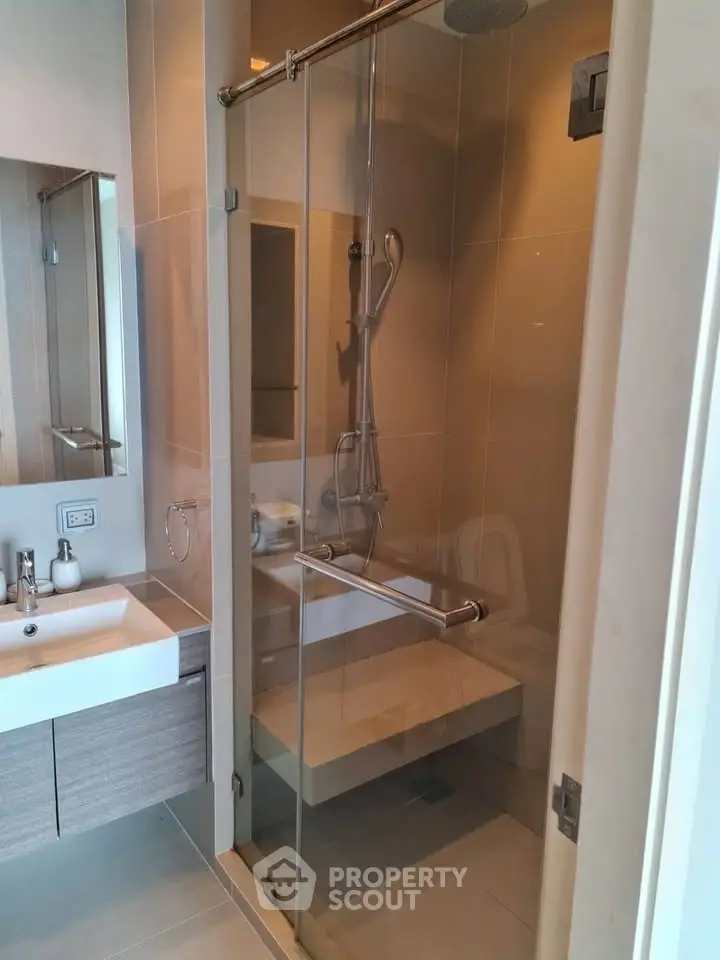 Modern bathroom with glass shower enclosure and sleek vanity in a contemporary apartment.